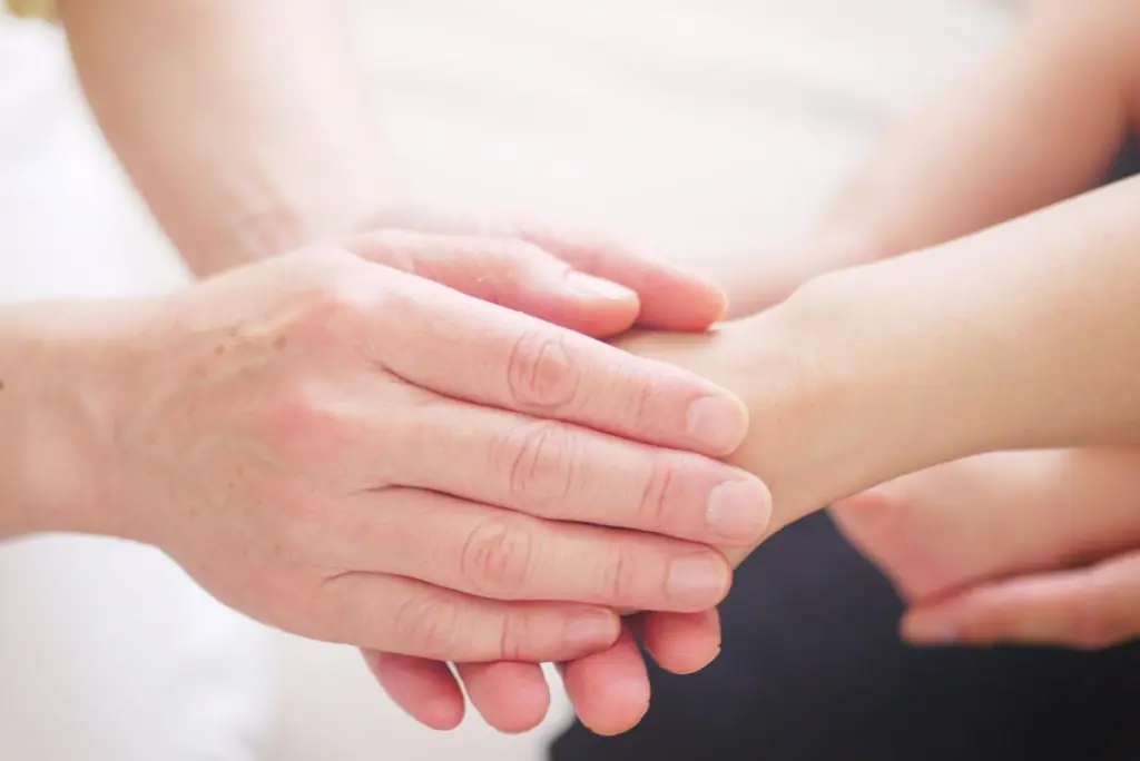 An adult holding children's hands